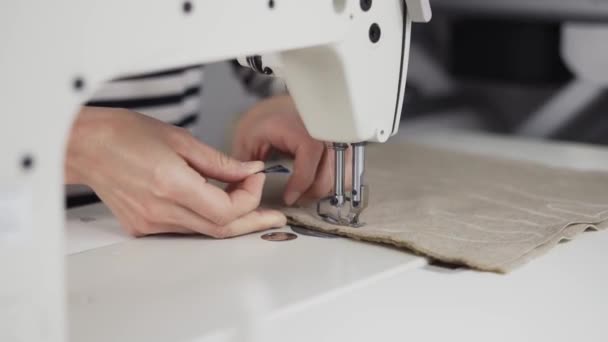 Primer plano de una joven mujer manos cosiendo tela beige con una máquina de coser — Vídeos de Stock