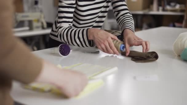 Zwei unkenntliche Näherinnen arbeiten mit Mustern und Stoffen auf dem Tisch — Stockvideo