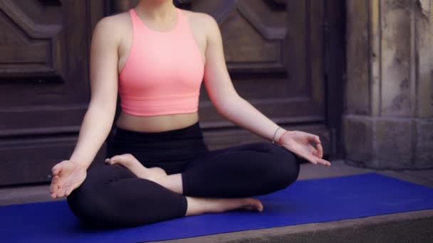 Идеальная сцена женщины, сидящей в позе лотоса в медитации над большой деревянной дверью — стоковое видео