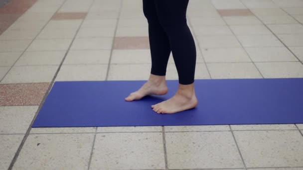 Primer plano de una mujer haciendo deporte al aire libre lugar de paso en estera de yoga — Vídeo de stock