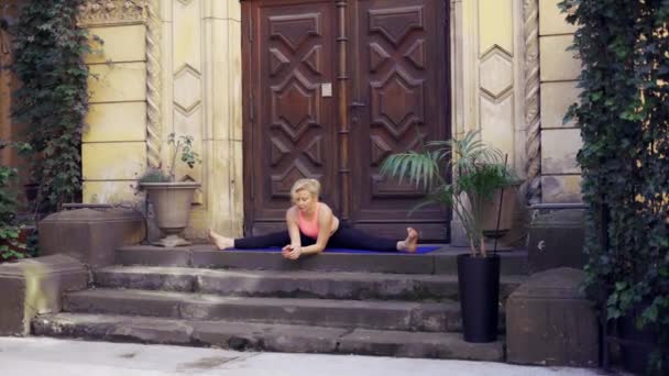 Femme faisant étirement en ficelle sur un porche sur une grande porte en bois — Video