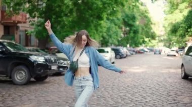 Şehir caddesinde asfalt yolda dans eden zarif bir kadın.