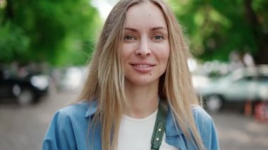 Yumuşak gülüşlü çekici bir Avrupalı kız, açık havada yürüyor.