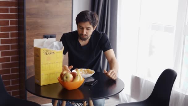 Kerel die cornflakes eet, kijkt naar de camera — Stockvideo