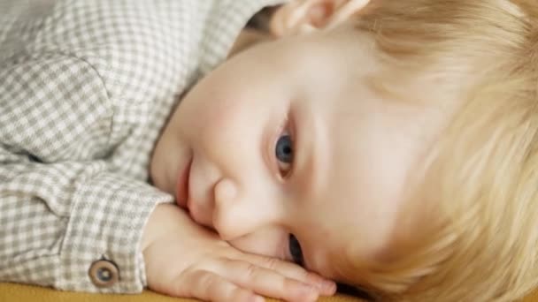 Κοντινό πλάνο πρόσωπο του χαριτωμένο μωρό νήπιο με μπλε μάτια που βρίσκεται χαμογελώντας — Αρχείο Βίντεο