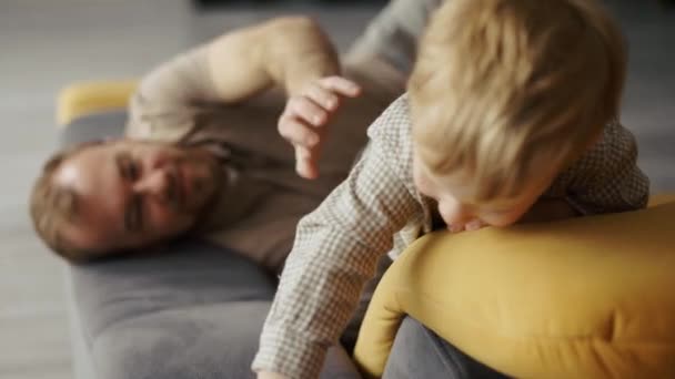Glad far leker med barn på soffan hemma — Stockvideo