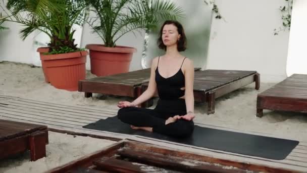 Здоровая женщина, занимающаяся йогой и медитацией на пляже — стоковое видео