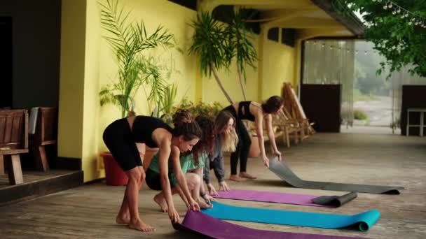 Alunos de aula de ioga unrolling tapetes no estúdio de ioga terraço — Vídeo de Stock