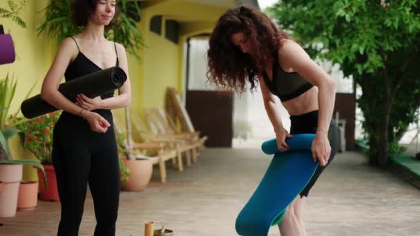 Jóvenes diversas personas descalzas plegando alfombras deportivas juntas, terminando la clase de yoga al aire libre — Vídeos de Stock