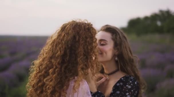 Twee sensuele vrouwen tussen een lavendelveld, die hun neus wrijven. — Stockvideo
