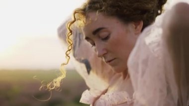 Mor bir tarlada pembe elbiseli kıvırcık saçlı kız.