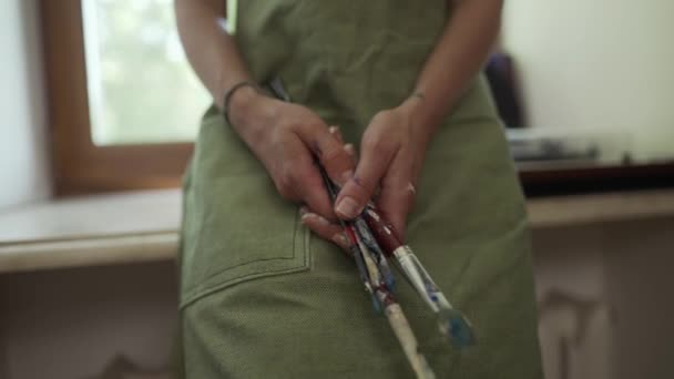 Unbekannter Künstler mit Schürze hält viele Pinsel in der Hand — Stockvideo