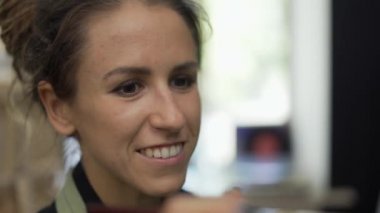 Sanat stüdyosunda neşeli bir kadın resim çiziyor.