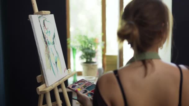 Γυναίκα καλλιτέχνης στην ποδιά ζωγραφική εικόνα σε καμβά στο στούντιο τέχνης — Αρχείο Βίντεο