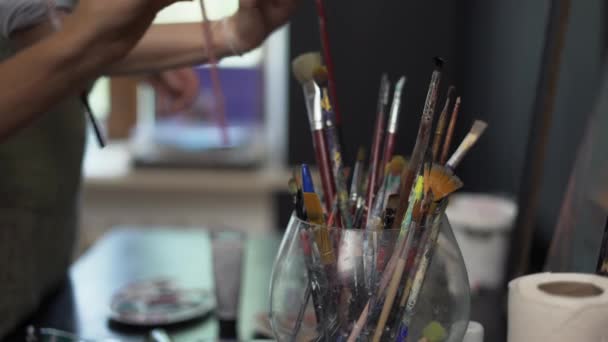 Mão de pintor tocando muitos pincéis no suporte de escova, close-up — Vídeo de Stock
