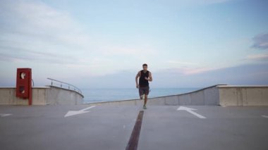 Atlet, boş bir otoparkın önünde hızla koşuyor.