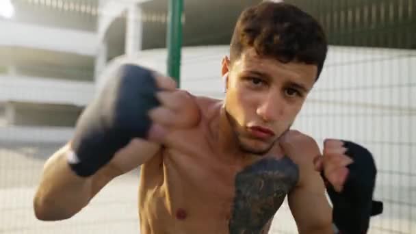 Boxer pratiquant des coups de poing dans la caméra avant à l'extérieur — Video