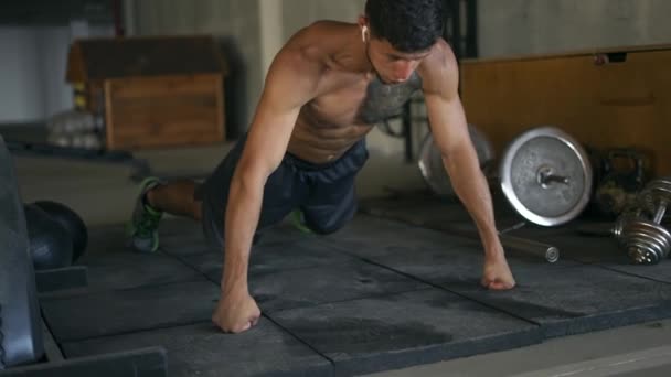 Hombre musculoso concentrado haciendo flexiones en el suelo en el gimnasio subterráneo — Vídeos de Stock