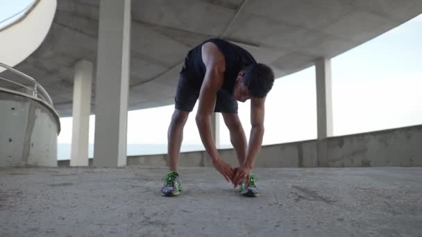 Atleta in abbigliamento sportivo si riscalda su un garage della città — Video Stock