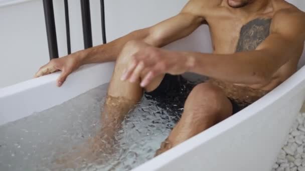 Muž sedí ve vaně s kostkami ledu pro zotavení a zdraví — Stock video
