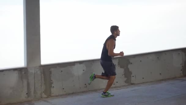 Atleta corre ao redor por níveis de uma garagem de estacionamento vazio — Vídeo de Stock