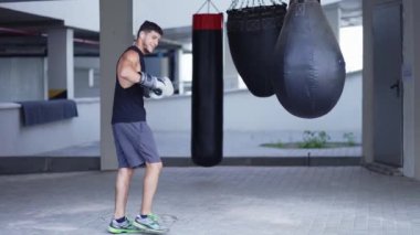 Farklı boks çantaları üzerinde kaslı erkek kickboksör eğitimi