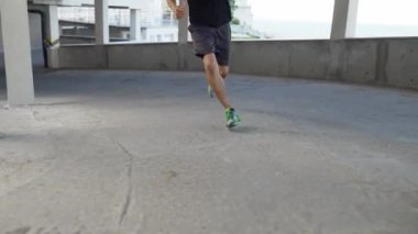 Tanımlanamayan bir sporcu boş bir otoparkın önünde koşuyor.