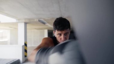 Dövüşçü park yerinde boks torbasında pratik yapıyor, yakın plan.