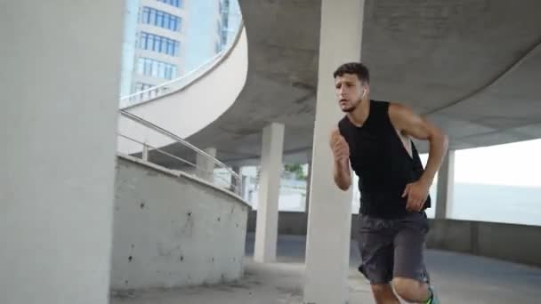 Спортсмен біжить по рівнях порожнього гаража, вид збоку — стокове відео