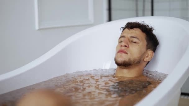 Muž sedí se zavřenýma očima ve vaně s kostkami ledu pro zotavení — Stock video