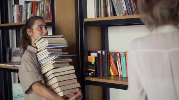 Dívka student drží hodně knih v knihovně, její přítel dal více