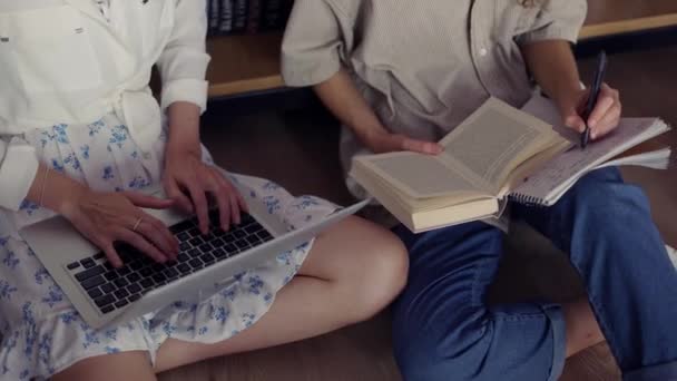 Estudiantes universitarias aprendiendo juntas en la biblioteca universitaria en el suelo, ángulo alto — Vídeo de stock