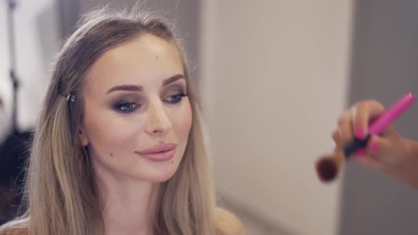 Makijażysta stosuje proszek do wykończenia makijażu klientów, zwolnione tempo — Wideo stockowe