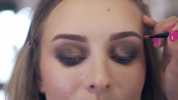 Maquillaje artista pinta las cejas con un pincel — Vídeo de stock