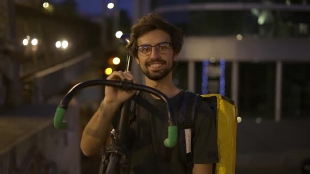 Kurier hält Fahrrad und Rucksack im Freien und lächelt — Stockvideo