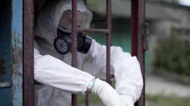 Korunma giysisi giyen bir adam, metal bir binanın içinde dikiliyor.