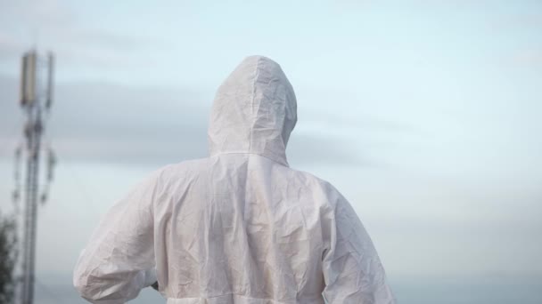 Uomo in tuta protettiva in piedi sul bordo del tetto mettere fuori il respiratore e cadere in ginocchio — Video Stock