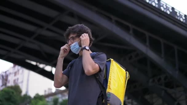 Messenger zet een medisch beschermend masker op, zijaanzicht — Stockvideo