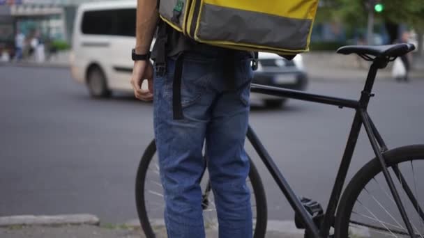 De levering staat met de fiets, te wachten op stadslicht verkeer — Stockvideo