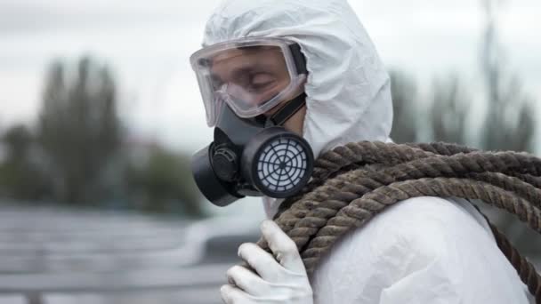 Worker in protective mask and respirator outdoors standing with ropes — Stock Video