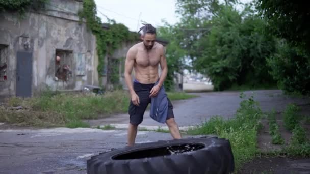 Pria berkaos mendorong naik roda besar dari traktor luar ruangan — Stok Video