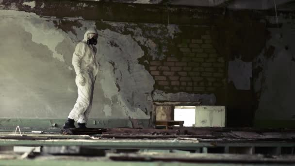 Worker in protection suit standing against destroyed brick wall in abandoned building — Stock Video