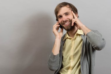 Happy smiling young man talking on mobile isolated on grey background