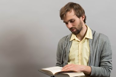 Portrait of a man reading a book. Isolated on gray