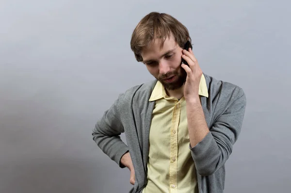 Un hombre hablando por teléfono. Sobre un fondo gris . — Foto de Stock