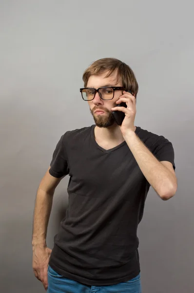 A man with a mobile phone on a gray background — Stockfoto