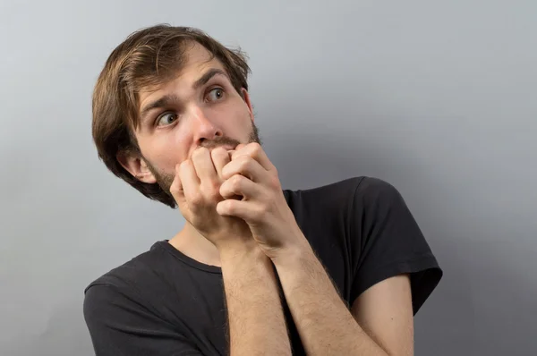 Un joven hombre de negocios mordiéndose las uñas. sobre un fondo de estudio gris claro — Foto de Stock