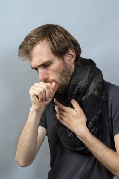 Yumruğuna öksüren bir adam. Gri arkaplan