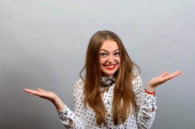 Güzel çekici rahat genç kadını kaldırdı elleriyle Studio gri arka plan üzerinde vurdu..