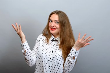 Güzel çekici rahat genç kadını kaldırdı elleriyle Studio gri arka plan üzerinde vurdu..